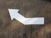 White painted arrow on concrete pavement indicating direction.